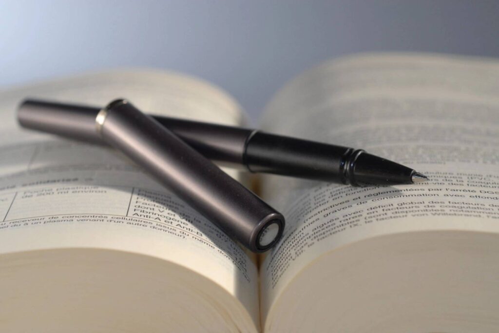 A pen and pencil sitting on top of an open book.