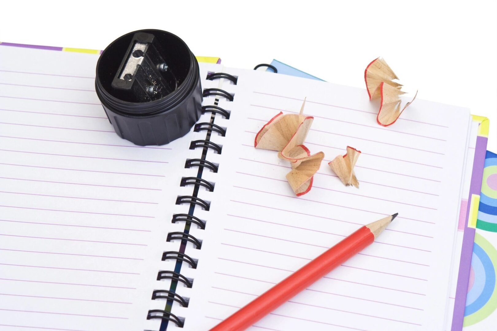 A pencil and sharpener on top of a notebook.